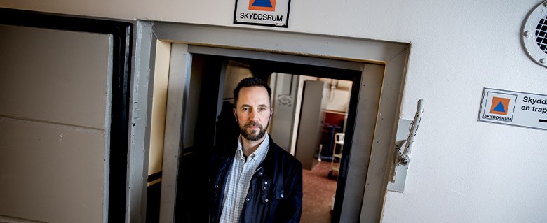 Bild på Lars Gråberg framför en skyddsrumsdörr.