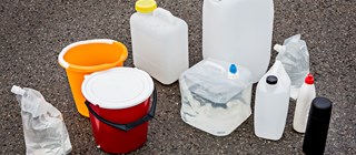 Vattendunkar, hinkar och flaskor med vatten står på asfalt.