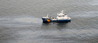 Kustbevakningsfartyg på vatten med oljespill.