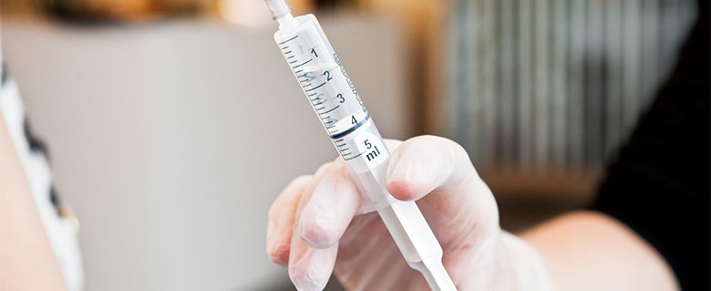 Sjukvårdspersonal håller vaccinationsspruta