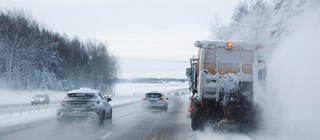 Plogbil plogar snö på motorväg.