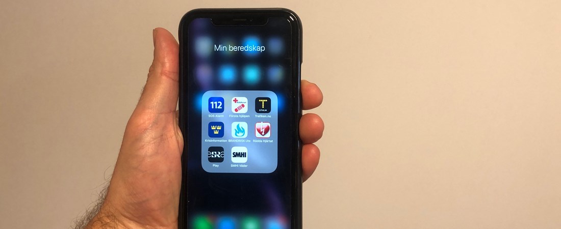 En hand som håller i en mobiltelefon. På skärmen syns alla appar som är listade i artikeln.