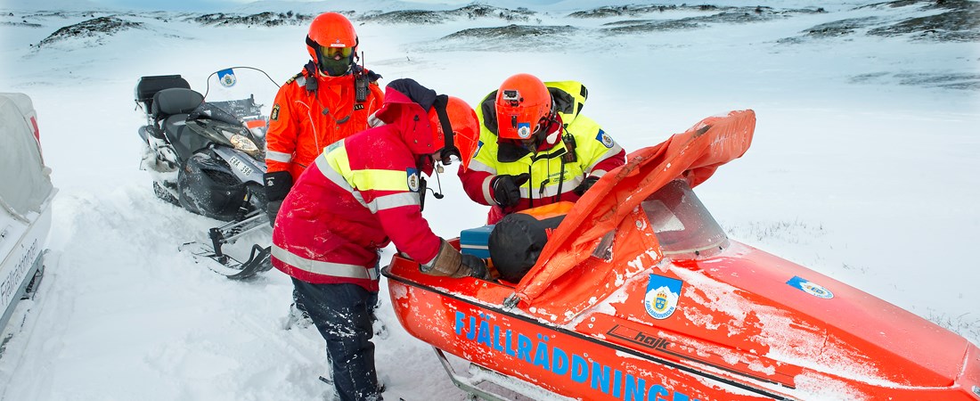 Tre fjällräddare under en räddningsinsats på ett snötäckt fjäll.