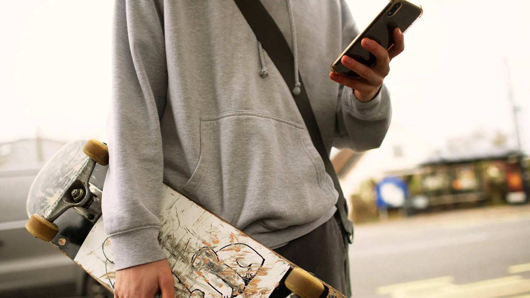 Barn med skateboard och mobiltelefon