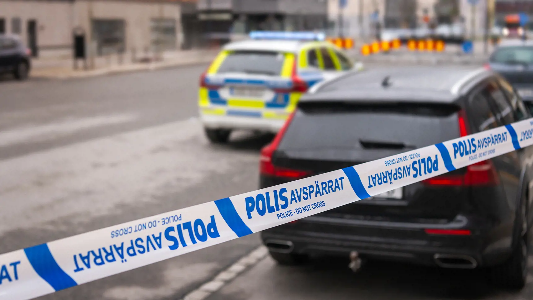 Polisavspärrning av en gata med en polisbil i bakgrunden.