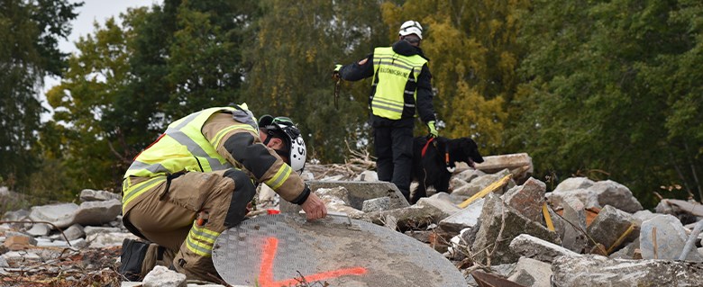 Bild på räddningspersonal som letar efter överlevande i rasmassor.