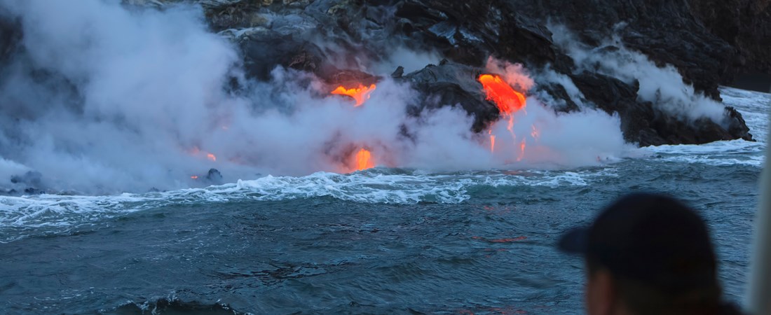Glödande lava från vulkanutbrott som väller ner i havet. 