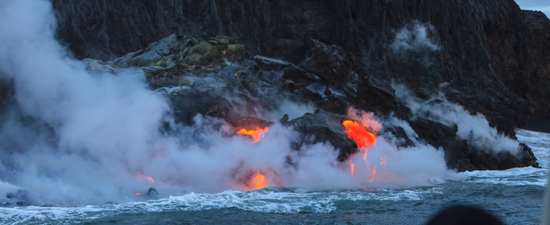 Vulkanutbrott på Hawaii. Lava syns rinna ned mot havet.