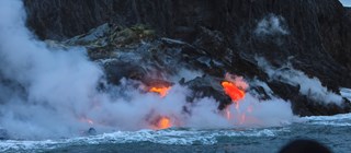 Vulkanutbrott på Hawaii. Lava syns rinna ned mot havet.