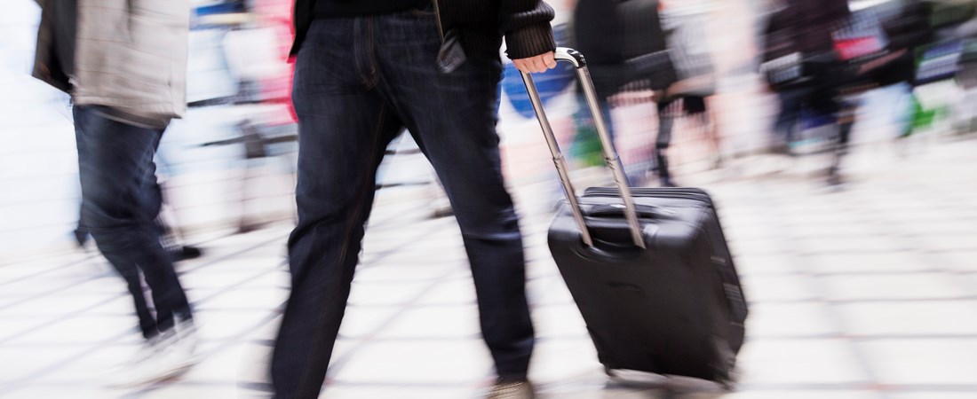 Passagerare som går med en väska på en flygplatsterminal.