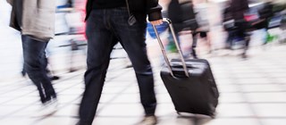 Passagerare som går med en väska på en flygplatsterminal.