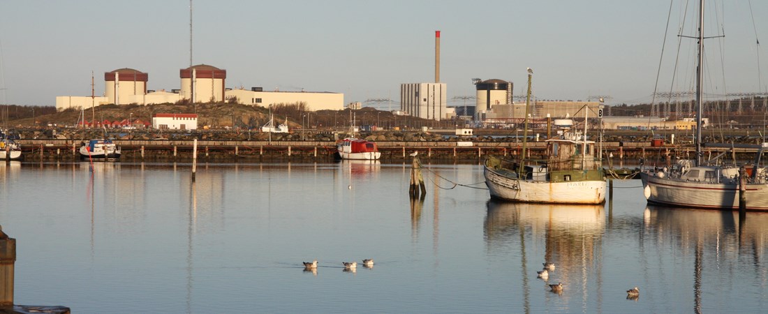 Ett stilla hav med båtar som ligger för ankar framför Oskarshamns kärnkraftverk.