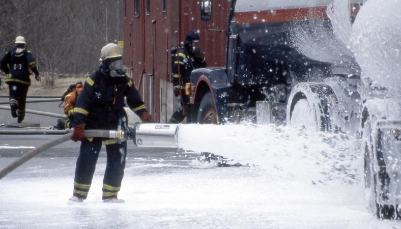 Brandmän som sprutar skum på en tankbil vid en trafikolycka