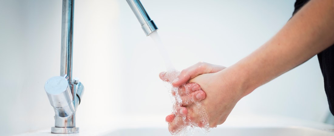 Händer som tvättas under en vattenkran.