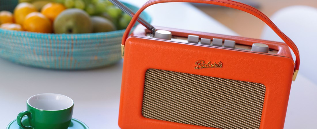 Radio på köksbord med fruktskål och kaffekopp.