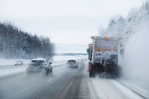 Plogbil plogar snö på motorväg.