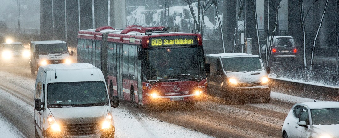 Buss och personbilar på en motorväg i snöoväder
