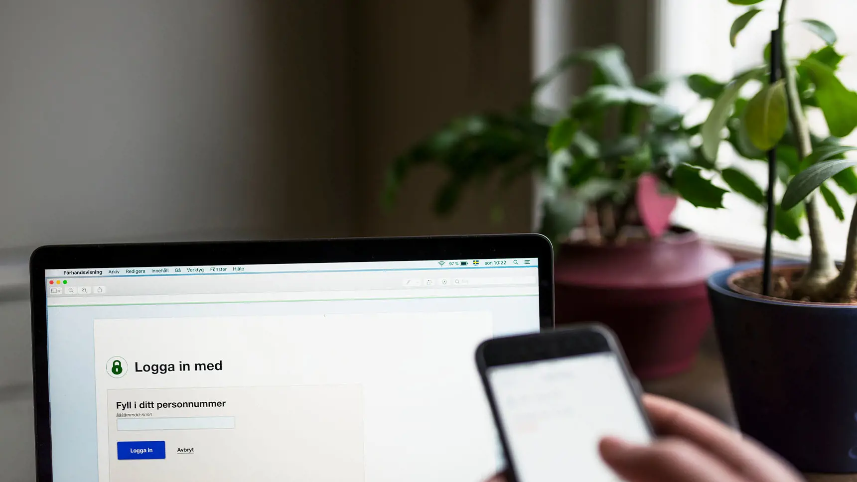 Person som loggar in i sitt bank-id med dator och mobiltelefon