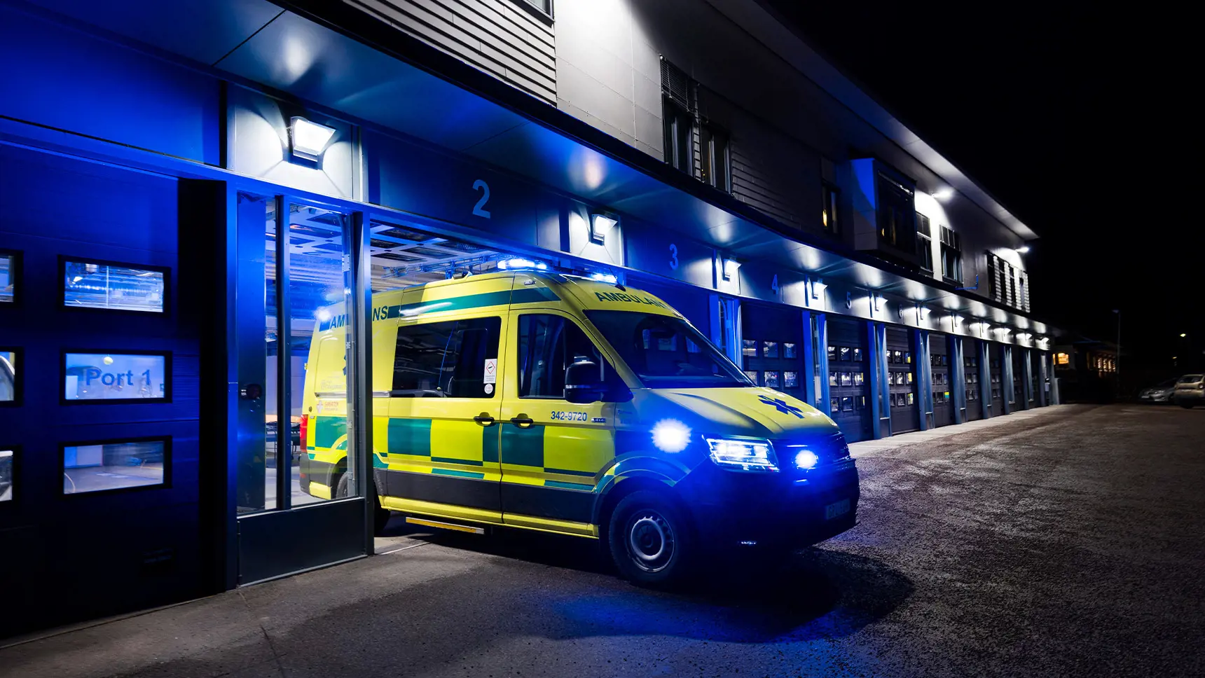 Ambulans som kör ut från ett sjukhus på natten.