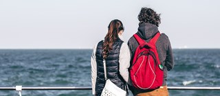 Ett par står vid en reling och blickar ut över havet. 