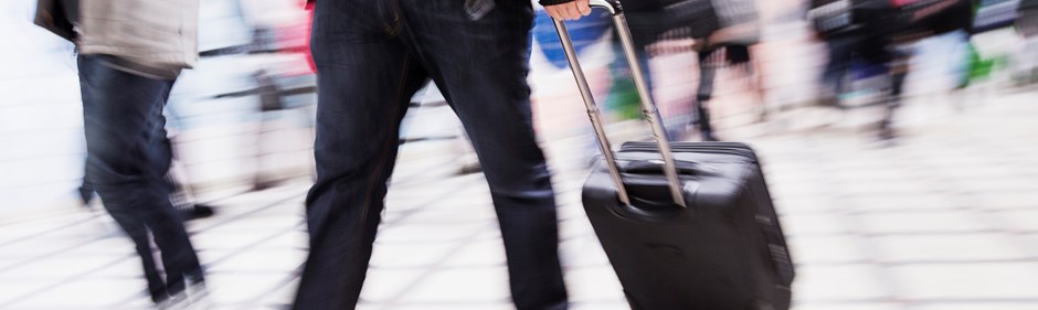Passagerare som går med en väska på en flygplatsterminal.