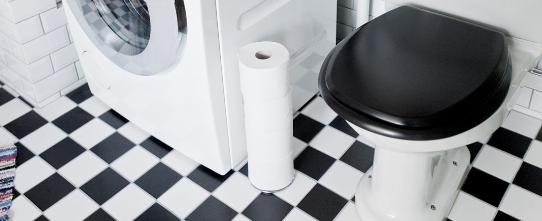 En tvättmaskin och toalett i ett svartvitt badrum. 