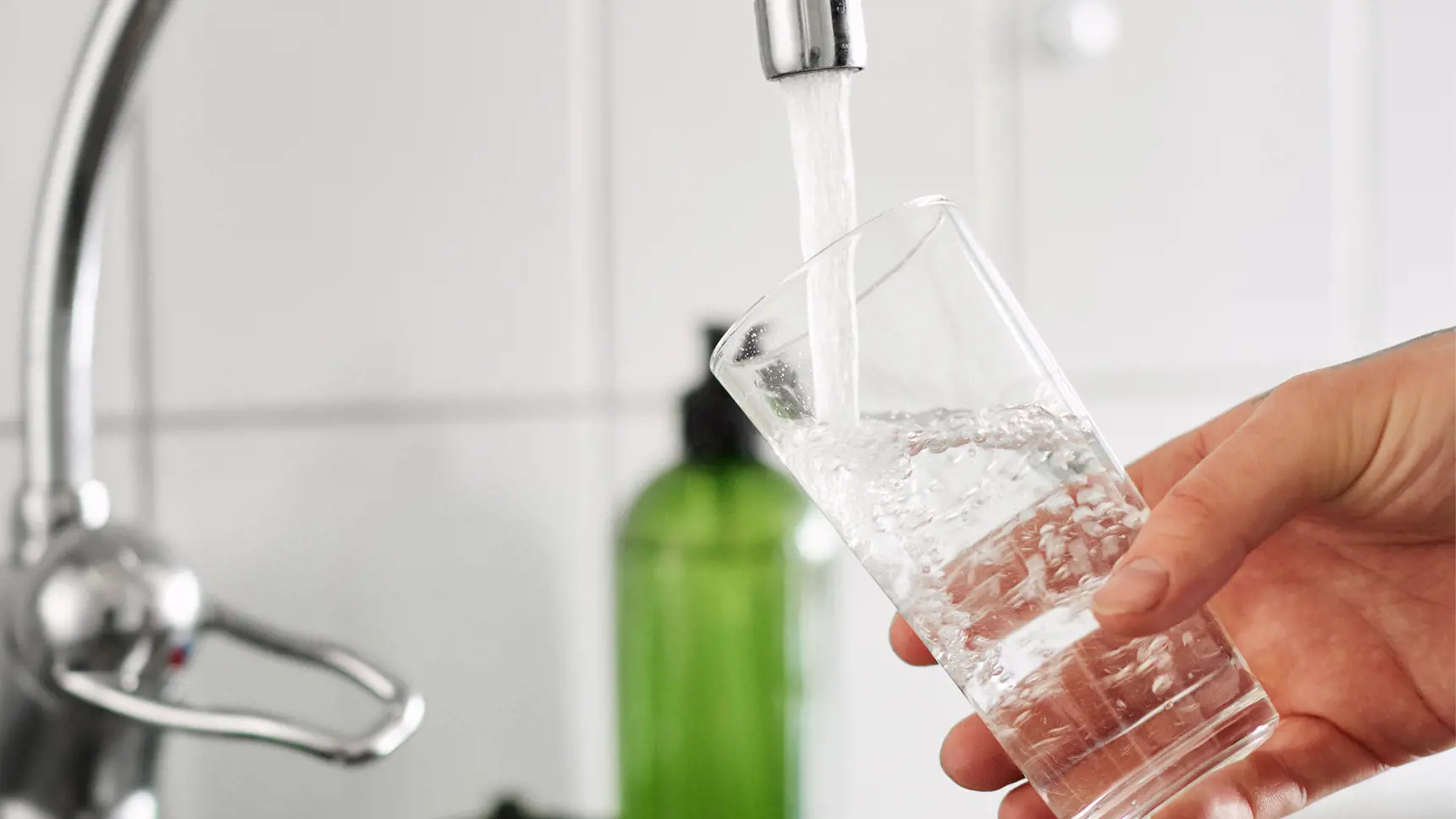 Glas fylls med vatten från vattenkran.