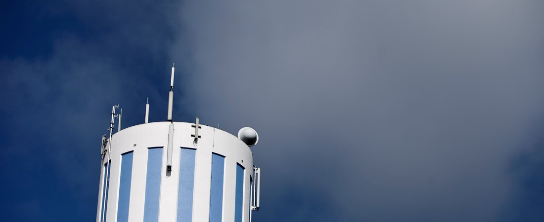 Blåvitrandigt vattentorn framför blå himmel. 