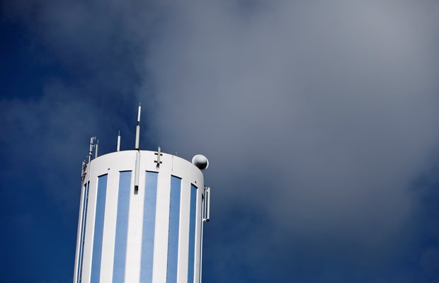 Blåvitrandigt vattentorn framför blå himmel. 