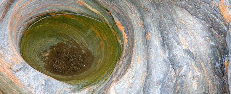 En slags jättegryta har formats i berget och är fylld med vatten.