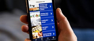 En hand som håller i en smartphone. På skärmen syns information från Krisinformation.se:s app.