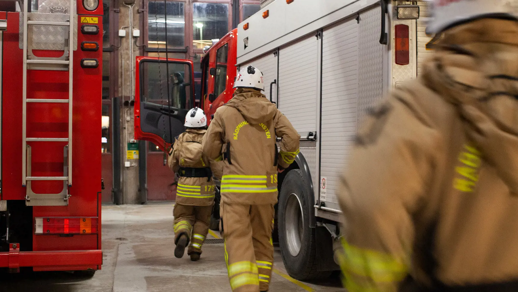 Brandmän på väg in i en brandbil som står i ett garage