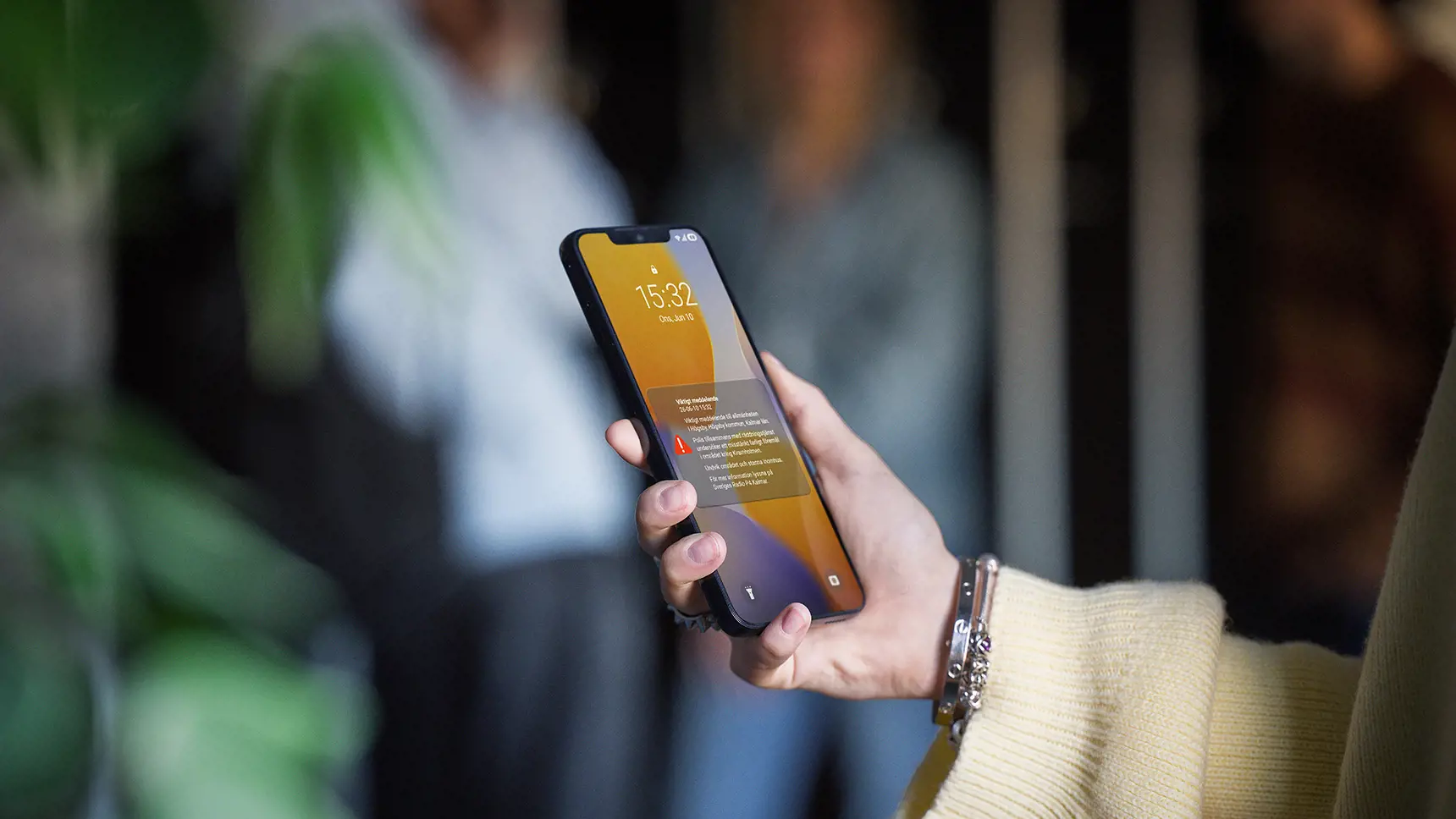 Hand håller i mobil som visar Viktigt meddelande till allmänheten.